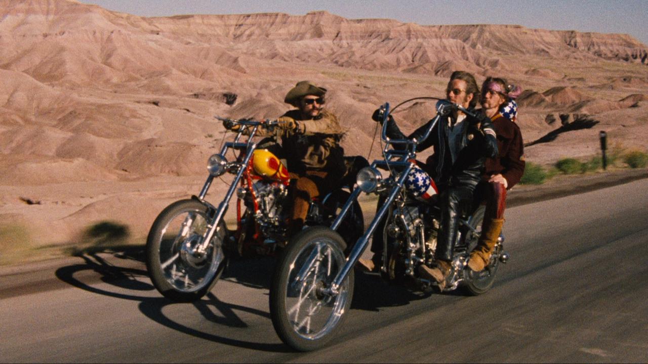 Image du film Easy Rider. Deux motos roulent sur une route désertique.