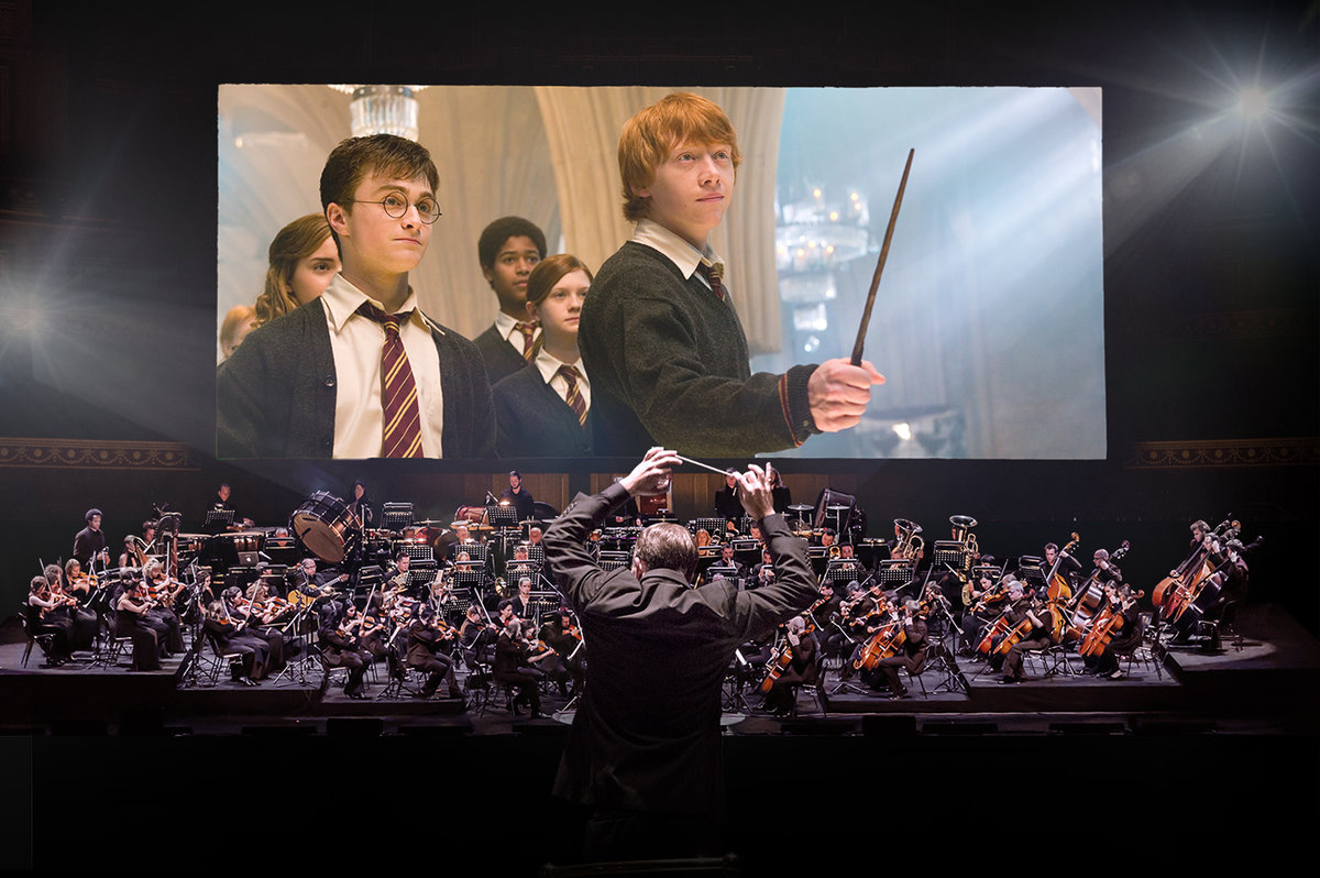 Un orchestre joue de la musique devant une projection de film de la série Harry Potter.