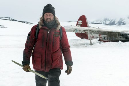Un homme vêtus d'habits hivernaux s'éloigne de l'épave d'un avion.