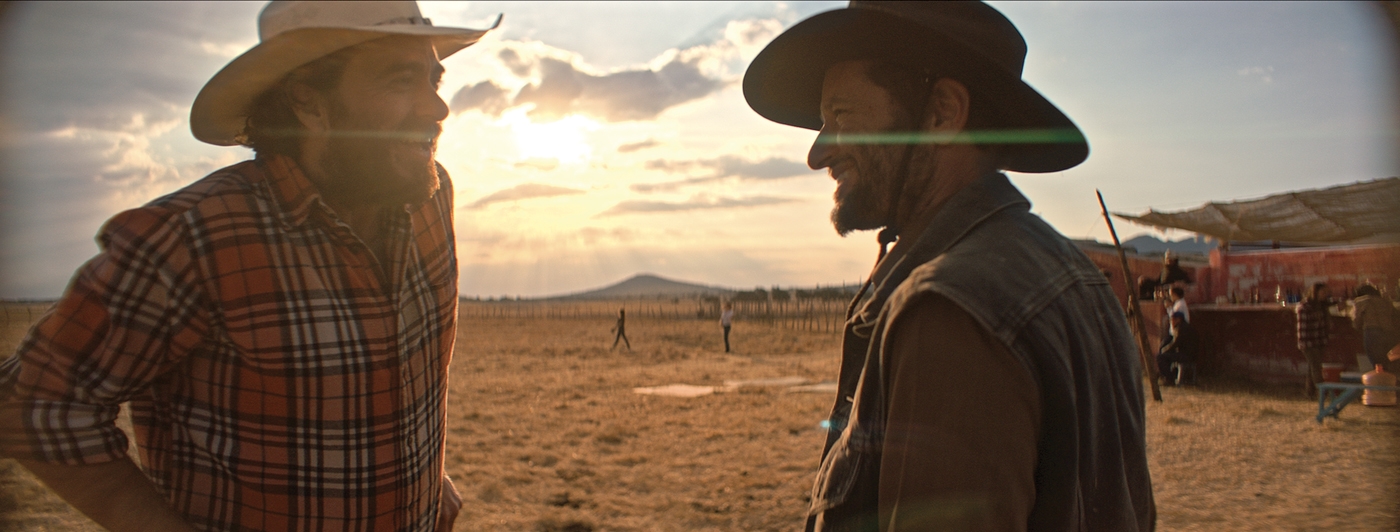 Deux cowboys s'observent au soleil couchant.